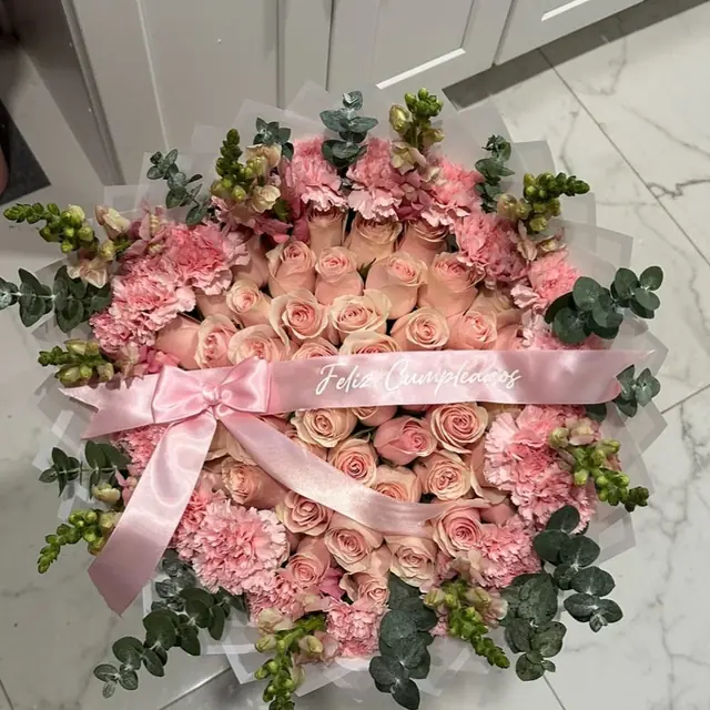 Pale pink and cream roses with carnations, eucalyptus and a pink satin ribbon